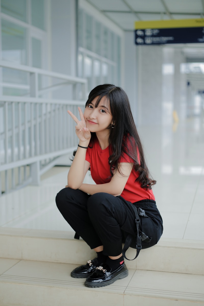 Photo by Chandri Anggara a woman sitting on a step making a peace sign